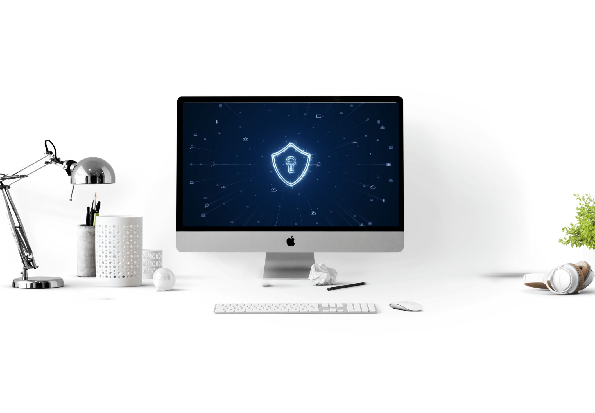 Auf dem Bildschirm eines Desktop-Computers wird ein digitales Sicherheitsschildsymbol angezeigt. Auf dem Schreibtisch stehen eine Lampe, ein Stifthalter, eine Tastatur, eine Maus, zerknülltes Papier, Kopfhörer und eine kleine Pflanze. Der Hintergrund ist weiß.