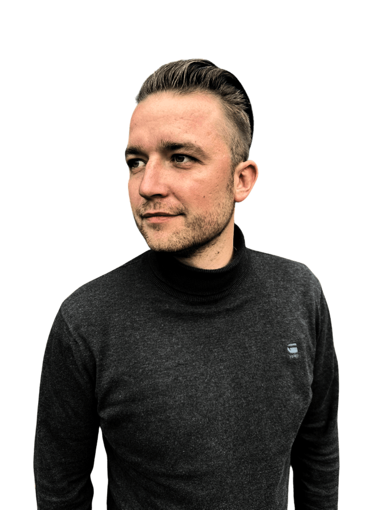 Eine Person mit kurzen Haaren und einem dunklen Rollkragenpullover blickt zur Seite. Der Hintergrund ist schwarz, was den nachdenklichen Gesichtsausdruck der Person unterstreicht.